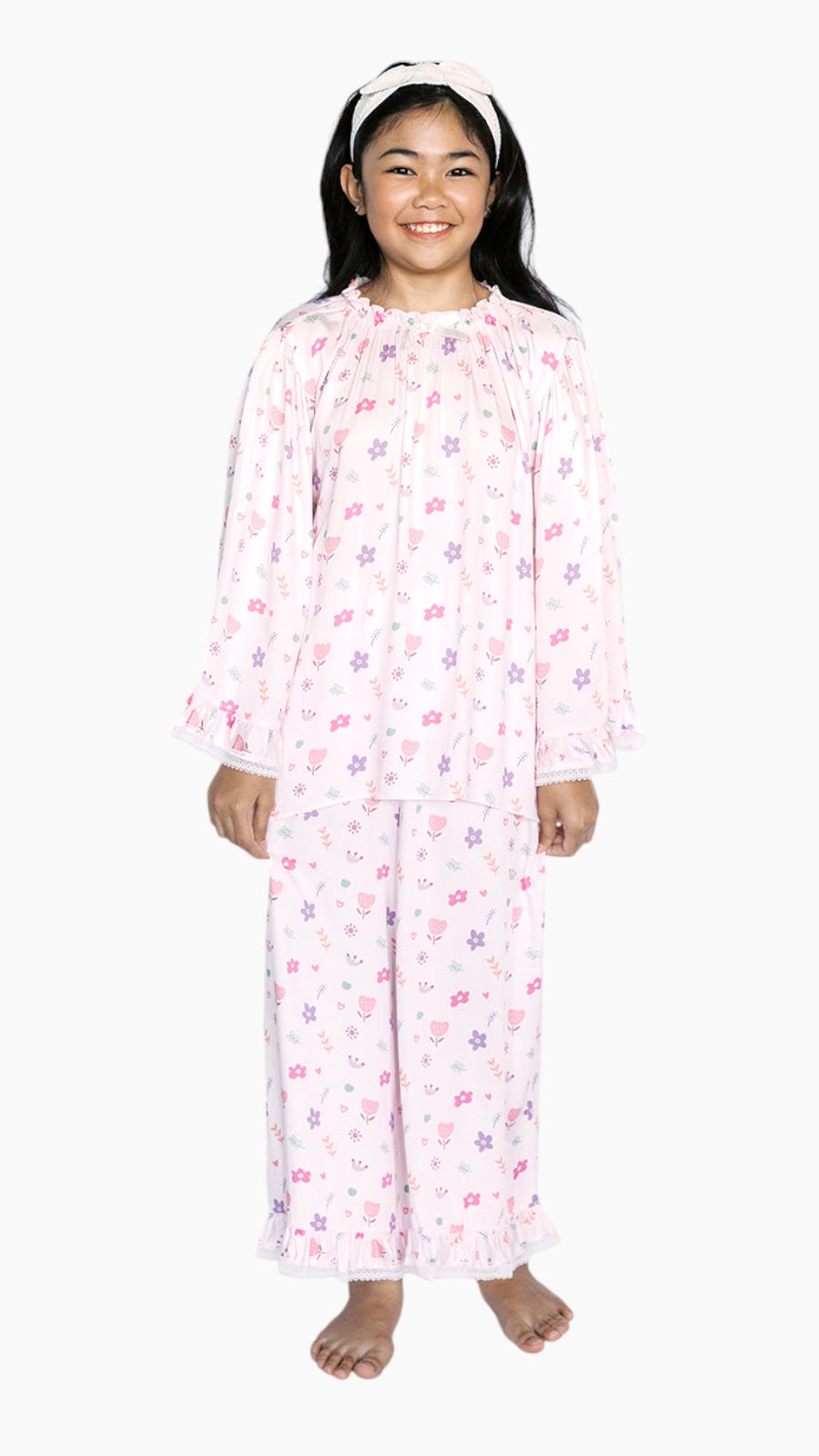Girl wearing a pink floral pajama set on a white background