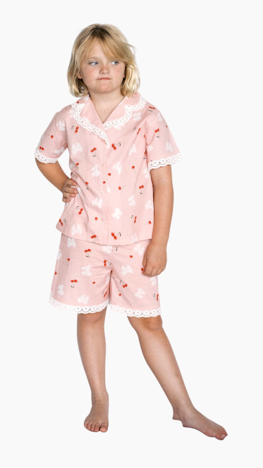 Child wearing a pink pajama set with cherry pattern on a white background