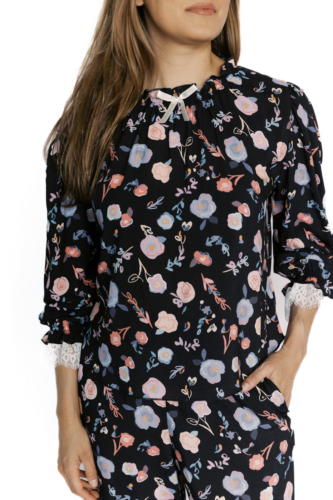 Woman wearing a black floral pajama set with long sleeves and pants.