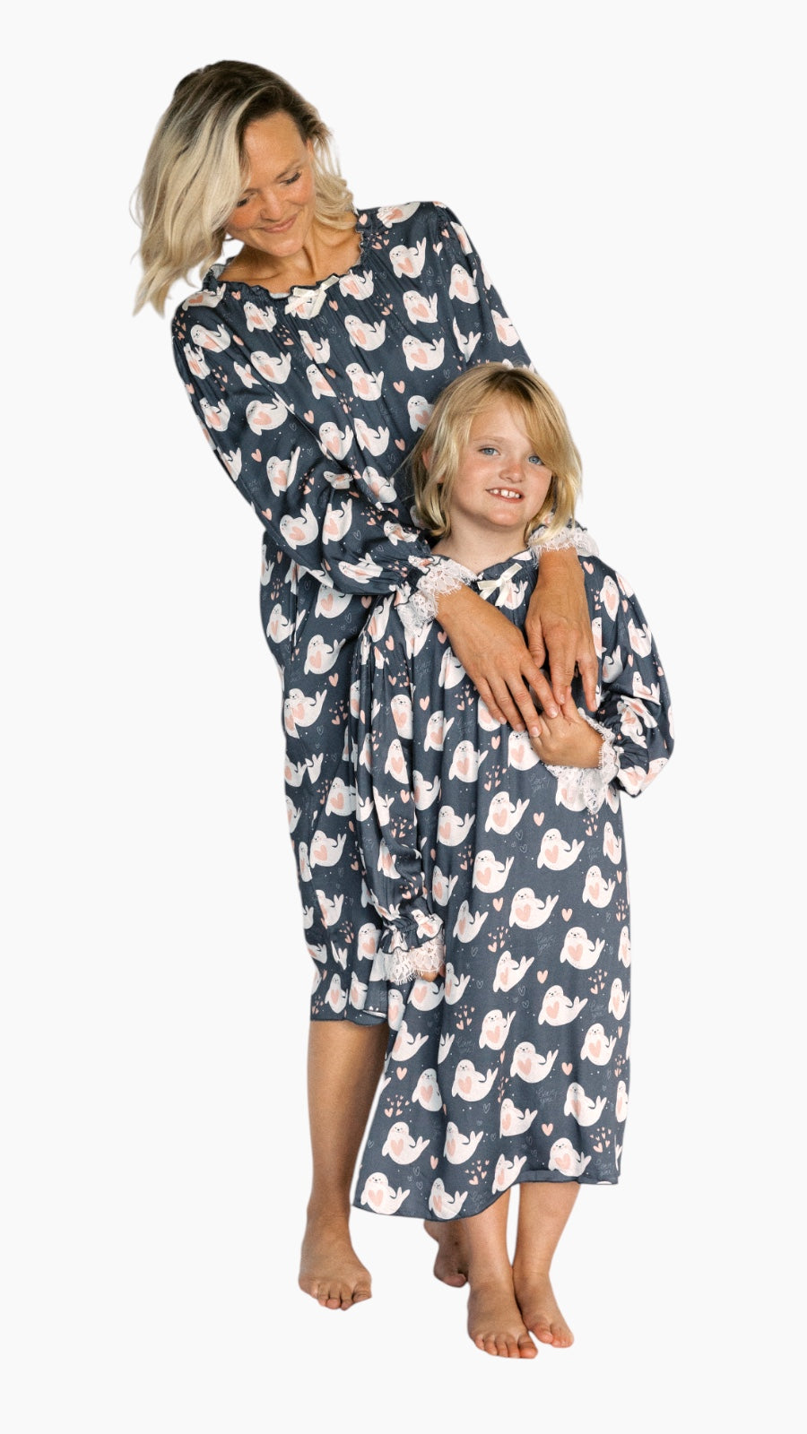 Woman and child wearing matching navy blue dresses with pink flamingo pattern on a white background