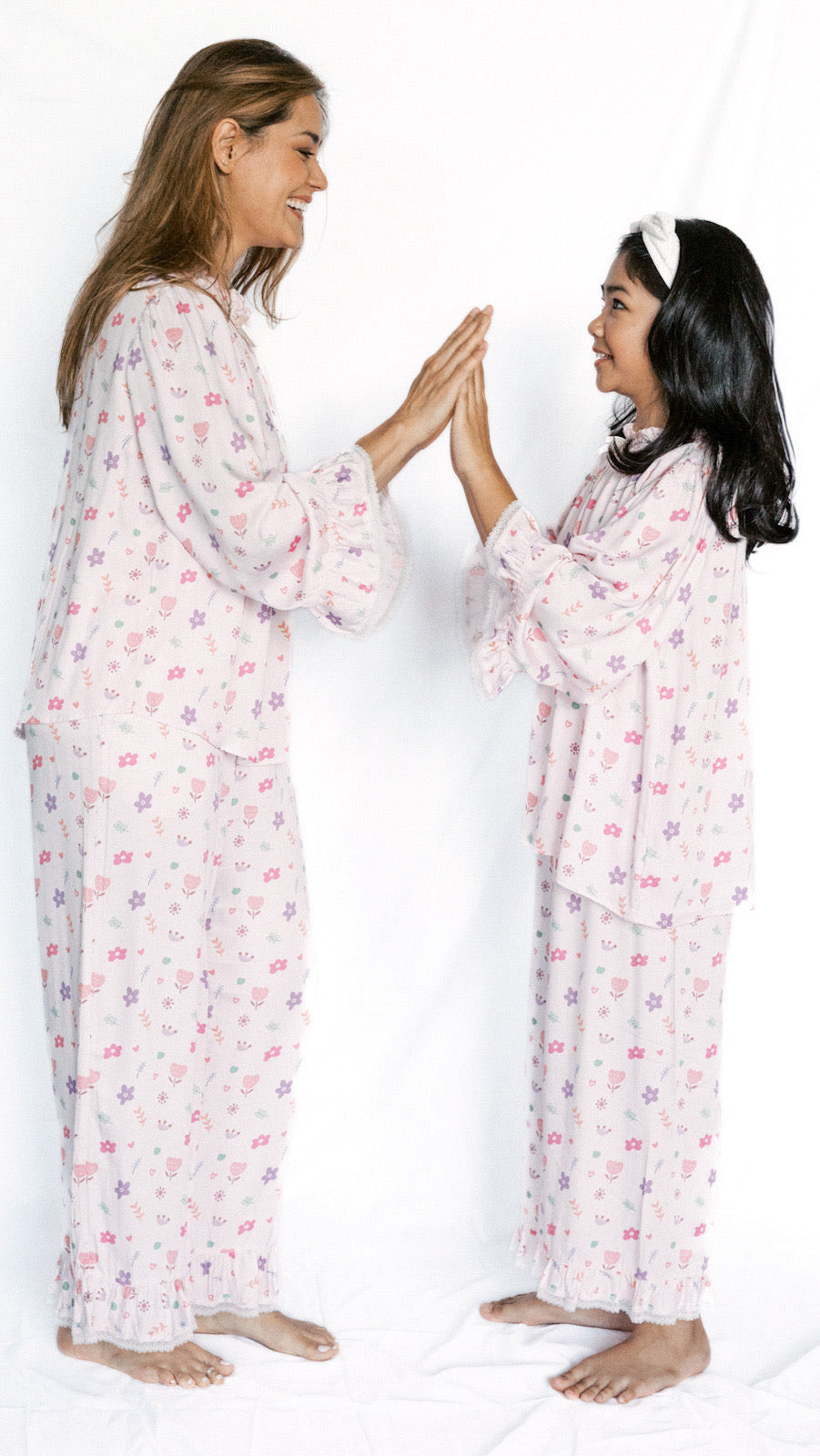 Two women wearing matching floral pajamas on a white background