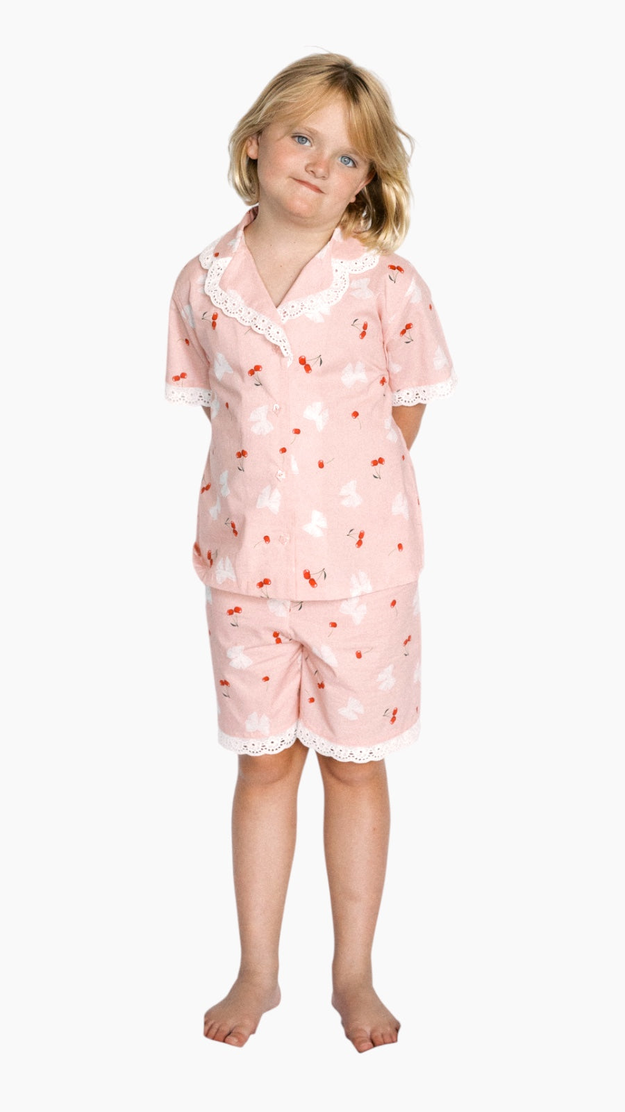 Child wearing a pink pajama set with cherry pattern on a white background