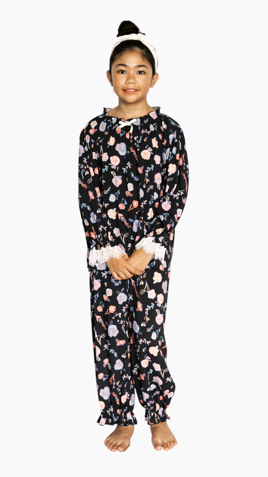 Young girl wearing a floral long PJs on a white background