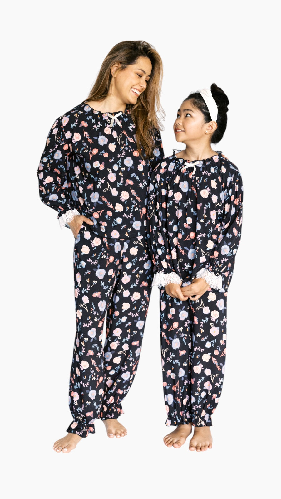 Woman and child wearing matching floral pajamas on a white background