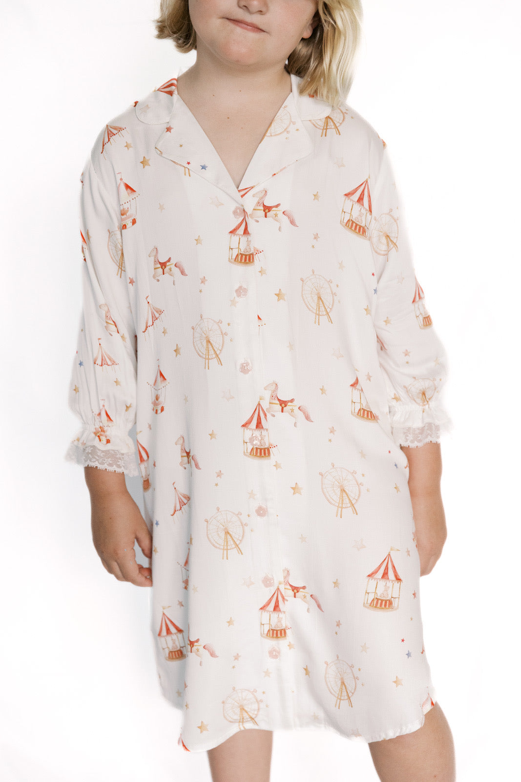 Child wearing a white nightgown with orange tent pattern on a white background