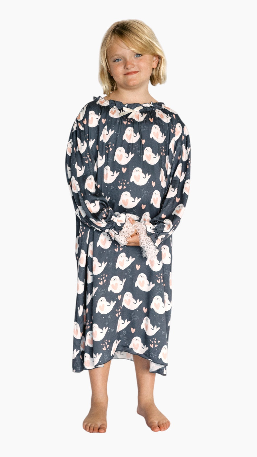 Child wearing a long-sleeve nightshirt with a seal love print on a white background